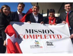 five people holding a mission completed sign