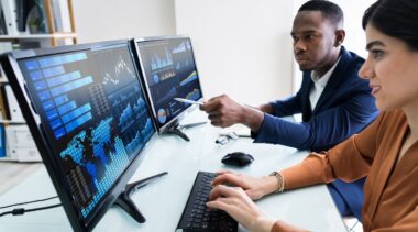 Photo of accounts looking at charts on computer screens