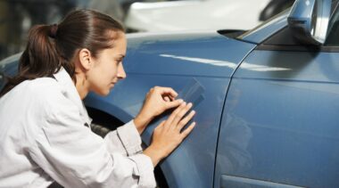 Photo of auto body repair technician looking at car body