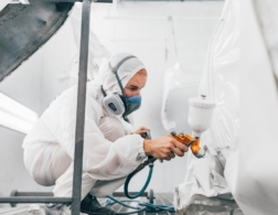 Photo of automotive refinishing using a spray gun to paint car