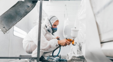 Photo of automotive refinishing using a spray gun to paint car