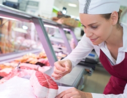 Photo of young butcher preparing meat at a counter