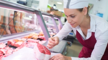 Photo of young butcher preparing meat at a counter