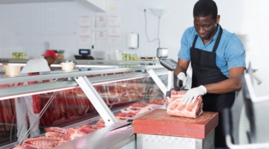 Photo of a young butcher cutting meat