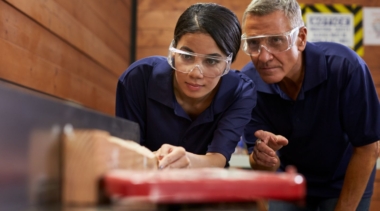 Photo of a young carpenter and a supervisor examining a piece of wood