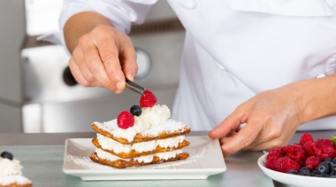 Photo of a confectionery chef placing a raspberry on a mille feuille