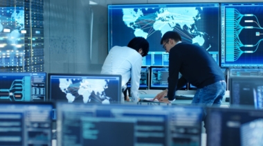Photo of two cyber intelligence officers in a control room with lots of computer screens