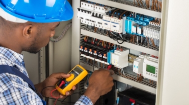 Photo of an electrician examining the inside of a fuse box