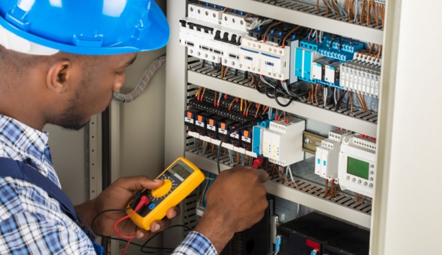 Photo of an electrician examining the inside of a fuse box