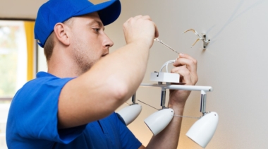 Photo of an electrician fixing a light fitting with a screwdriver