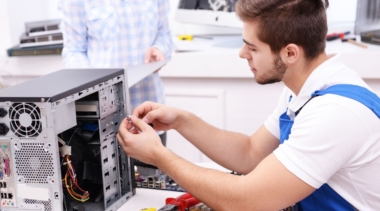 Photo of an electronics technician examining the inside of a computer