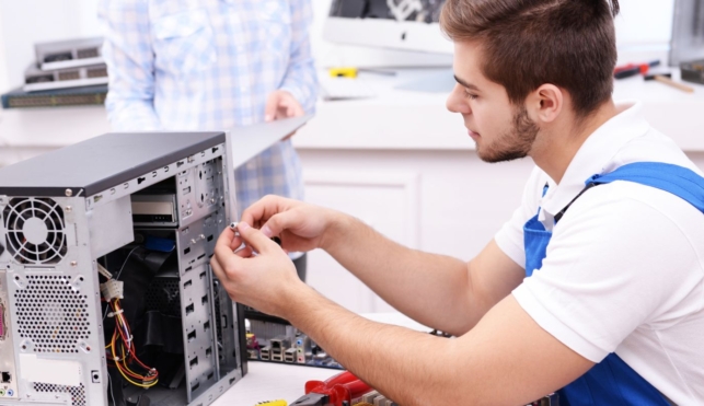 Photo of an electronics technician examining the inside of a computer