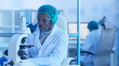 Photo of forensic scientist looking into microscope