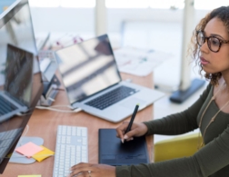 Photo of graphic designer using electronic drawing pad to sketch onto computer