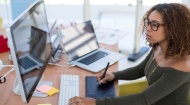 Photo of graphic designer using electronic drawing pad to sketch onto computer