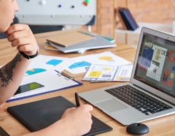 Photo of graphic designer using electronic drawing pad to sketch onto computer