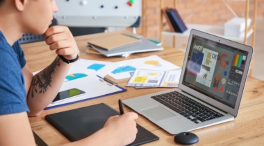 Photo of graphic designer using electronic drawing pad to sketch onto computer