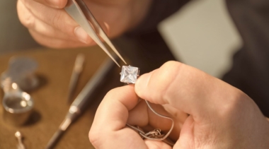 Photo of jeweller holding a diamond close up with tweezers