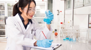 Photo of young lab technician examining contents of a conical beaker