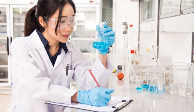 Photo of young lab technician examining contents of a conical beaker