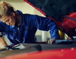 Photo of a young female mechanic examining under the hood of a car