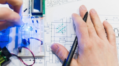 Photo of a mechatronics engineer examining a small component part and a drawing