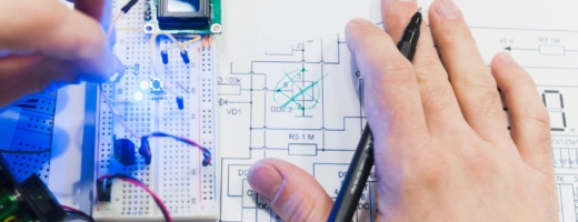 Photo of a mechatronics engineer examining a small component part and a drawing