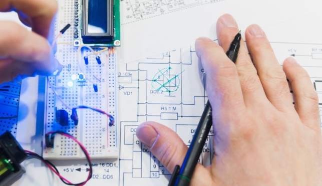 Photo of a mechatronics engineer examining a small component part and a drawing