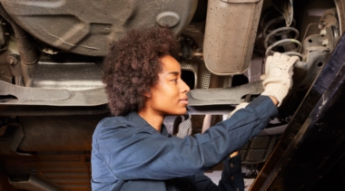 Photo of a young mechatronics engineer examining the underside of a machine