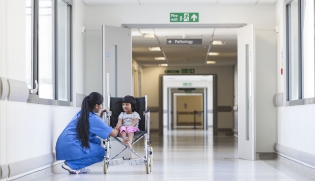 Photo of nurse talking to child patient sat in a wheelchair