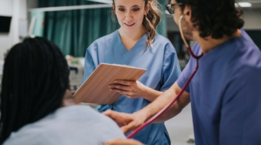Photo of nurse with patient writing on clipboard