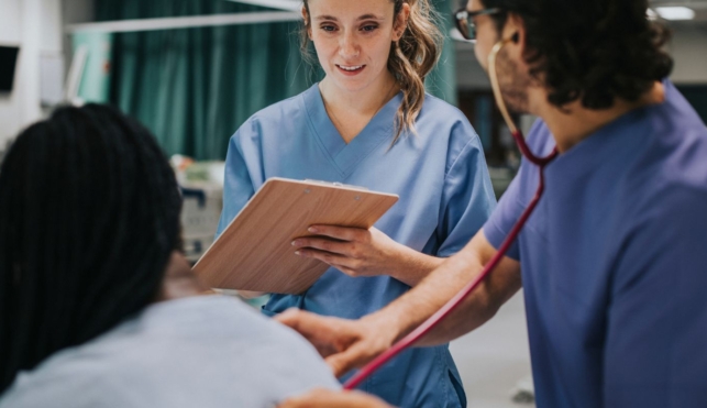 Photo of nurse with patient writing on clipboard