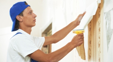 Photo of a painter and decorator pulling off wallpaper from a wall