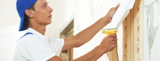 Photo of a painter and decorator pulling off wallpaper from a wall