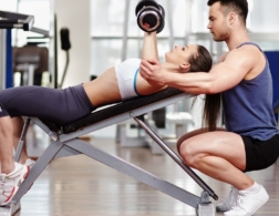 Photo of a personal trainer helping a client to lift weights
