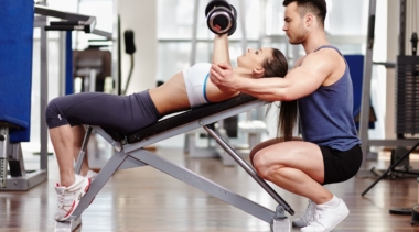 Photo of a personal trainer helping a client to lift weights