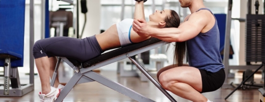 Photo of a personal trainer helping a client to lift weights