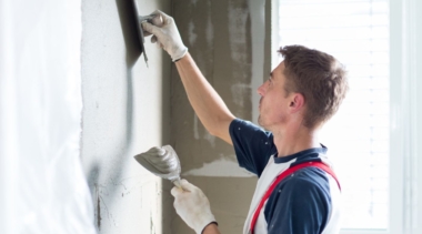 Photo of a young plasterer and drywall worker with a trowel and hawk tool