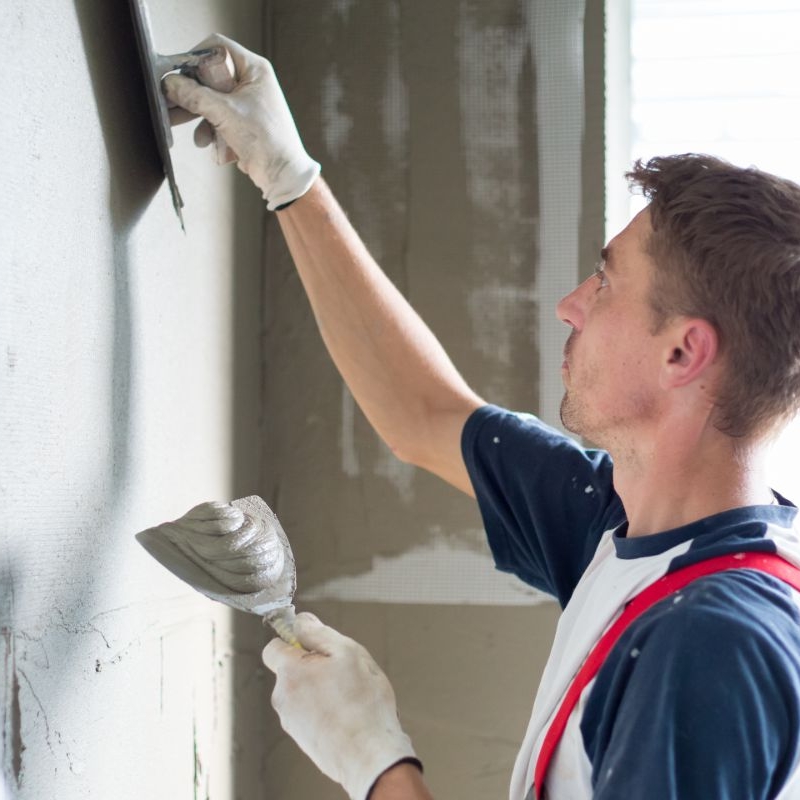 Photo of a young plasterer and drywall worker with a trowel and hawk tool