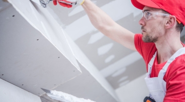 Photo of a young plasterer and drywall worker with a trowel and hawk tool