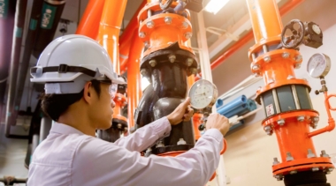 Photo of a young refrigeration engineer examining a dial on pipework