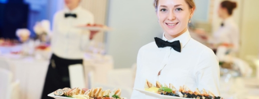 Photo of a young waitress in a restaurant serving platters of food