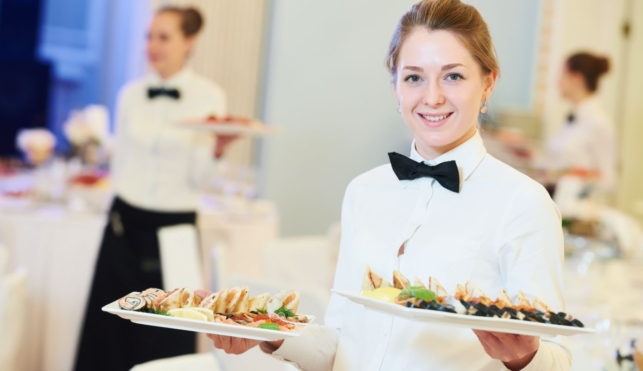 Photo of a young waitress in a restaurant serving platters of food