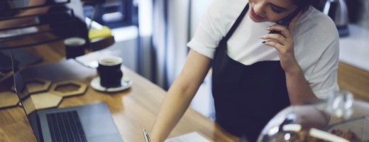 Photo of a young restaurant manager in an apron taking bookings over the phone