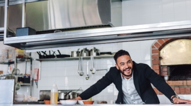 Photo of a young restaurant manager leaning over the serving pass in a restaurant