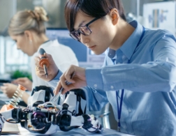 Photo of young robotics engineer using tools to work on a robot