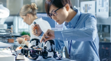 Photo of young robotics engineer using tools to work on a robot