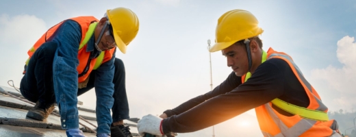 Photo of two roofers in yellow hard hats fixing batons to a roof