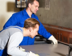 Photo of two sheet metalworkers inspecting a piece of sheet metal