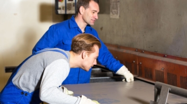 Photo of two sheet metalworkers inspecting a piece of sheet metal